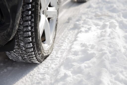 Automobilist die de profieldiepte van een winterband controleert voor het herfstseizoen