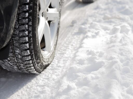 Automobilist die de profieldiepte van een winterband controleert voor het herfstseizoen