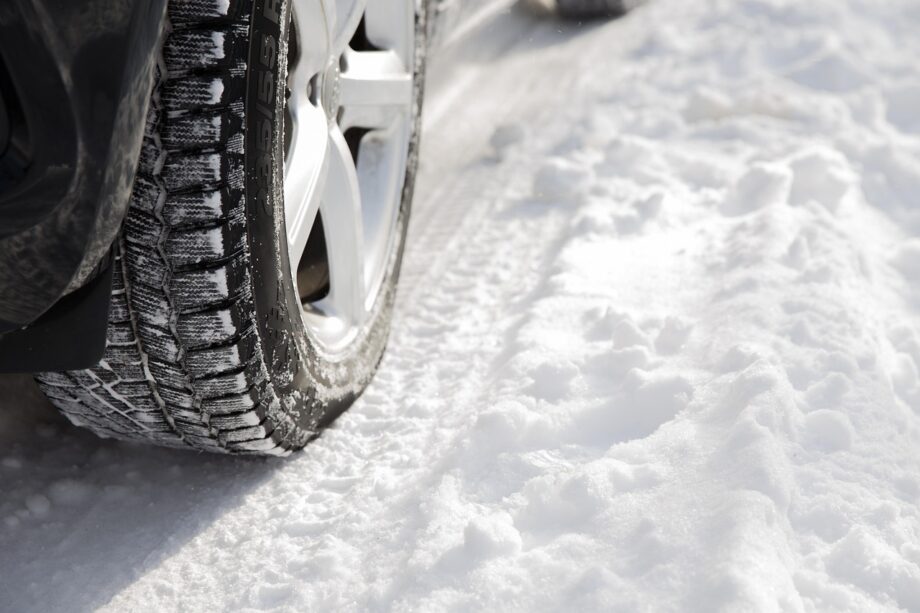 Automobilist die de profieldiepte van een winterband controleert voor het herfstseizoen
