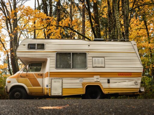Een camper op een bosweg omringd door kleurrijke herfstbomen