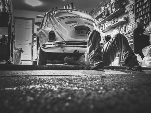 Volwassen student leert autotechniek in een werkplaats naast een monteur