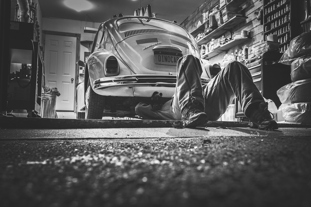 Volwassen student leert autotechniek in een werkplaats naast een monteur