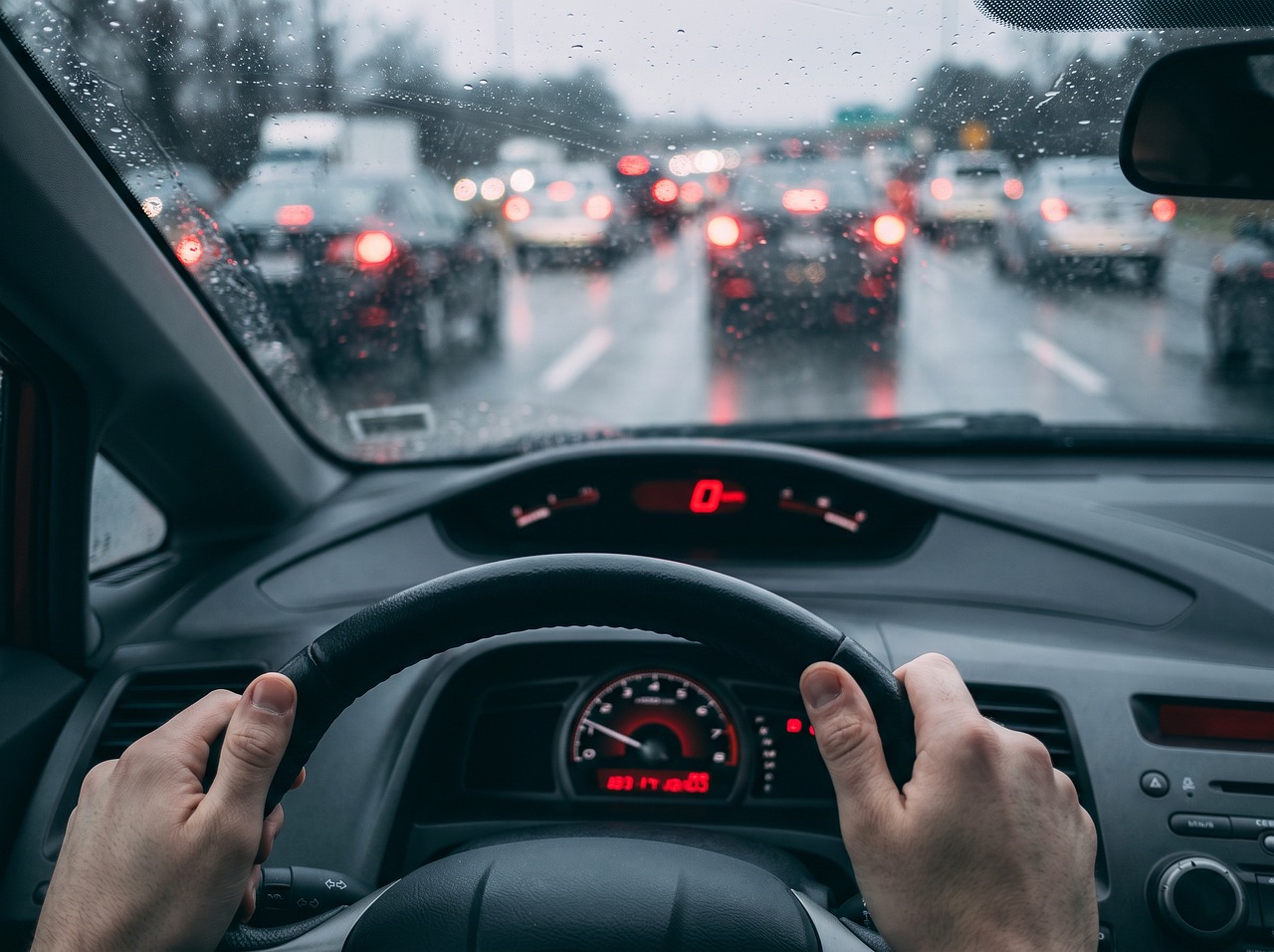 Nat asfalt op een Nederlandse snelweg met remmende auto's in de regen